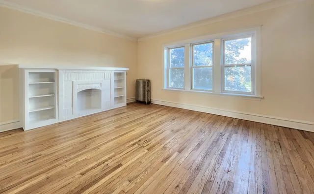 a view of an empty room with a window and wooden floor