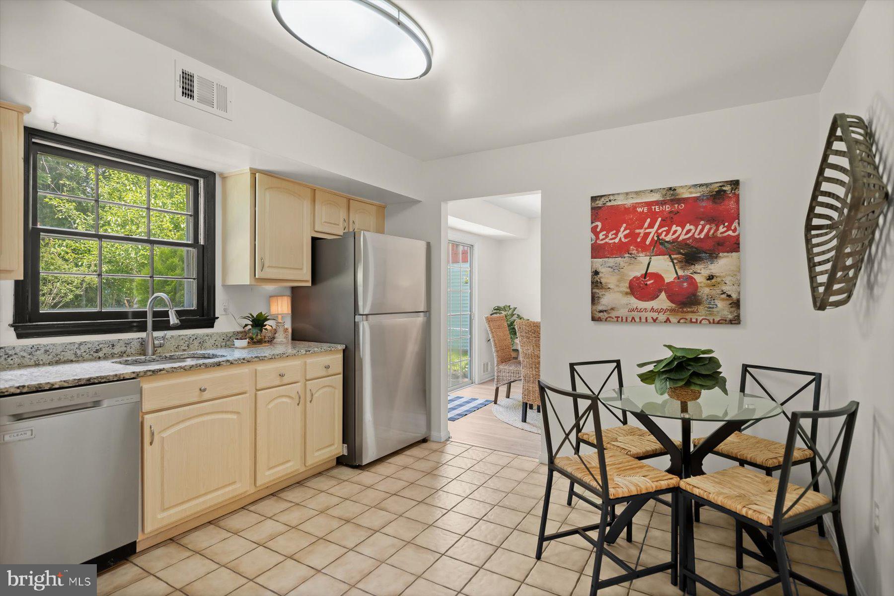 6819 Ben Franklin Road Springfield, VA 22150 - Photo 11 of 47 a kitchen with stainless steel appliances a table chairs and a refrigerator