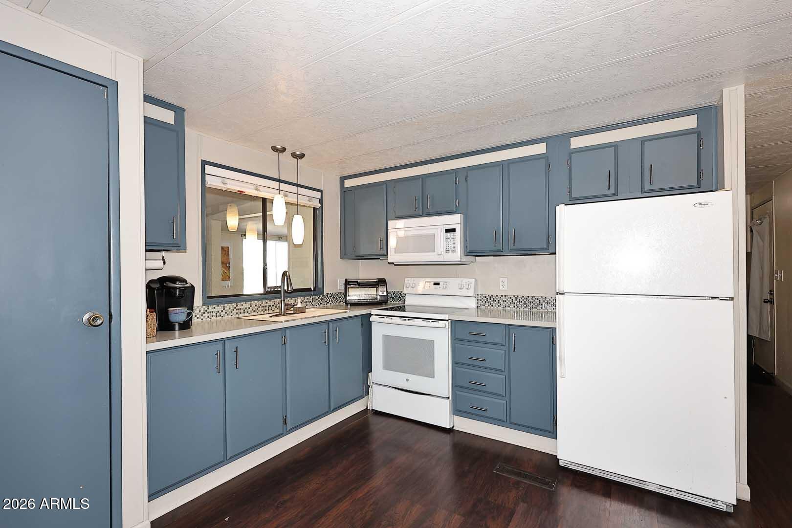 a kitchen with sink a refrigerator and white cabinets
