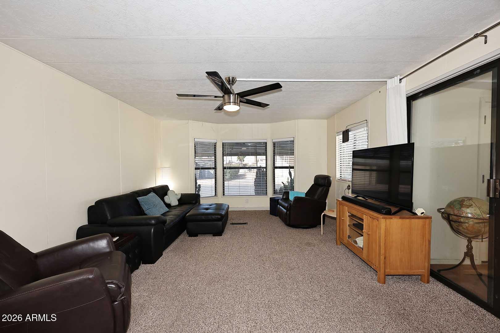9302 East Broadway Road, Unit 76 Mesa, AZ 85208 - Photo 34 of 38 a living room with furniture ceiling fan and a flat screen tv