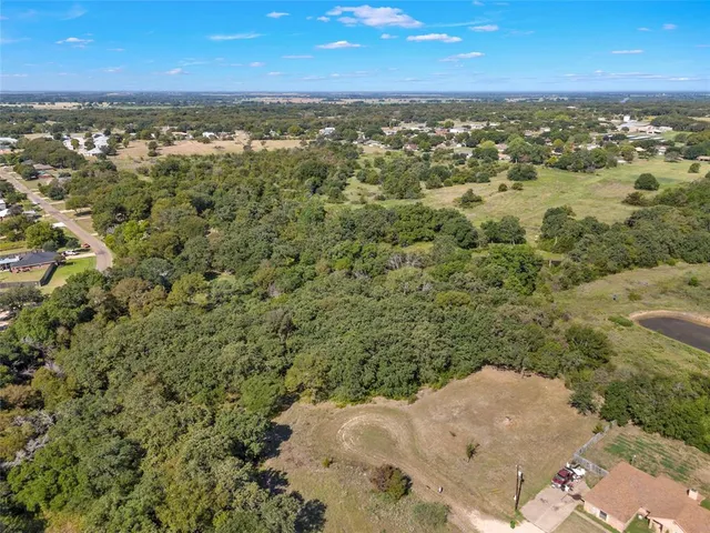 an aerial view of residential houses with outdoor space and trees