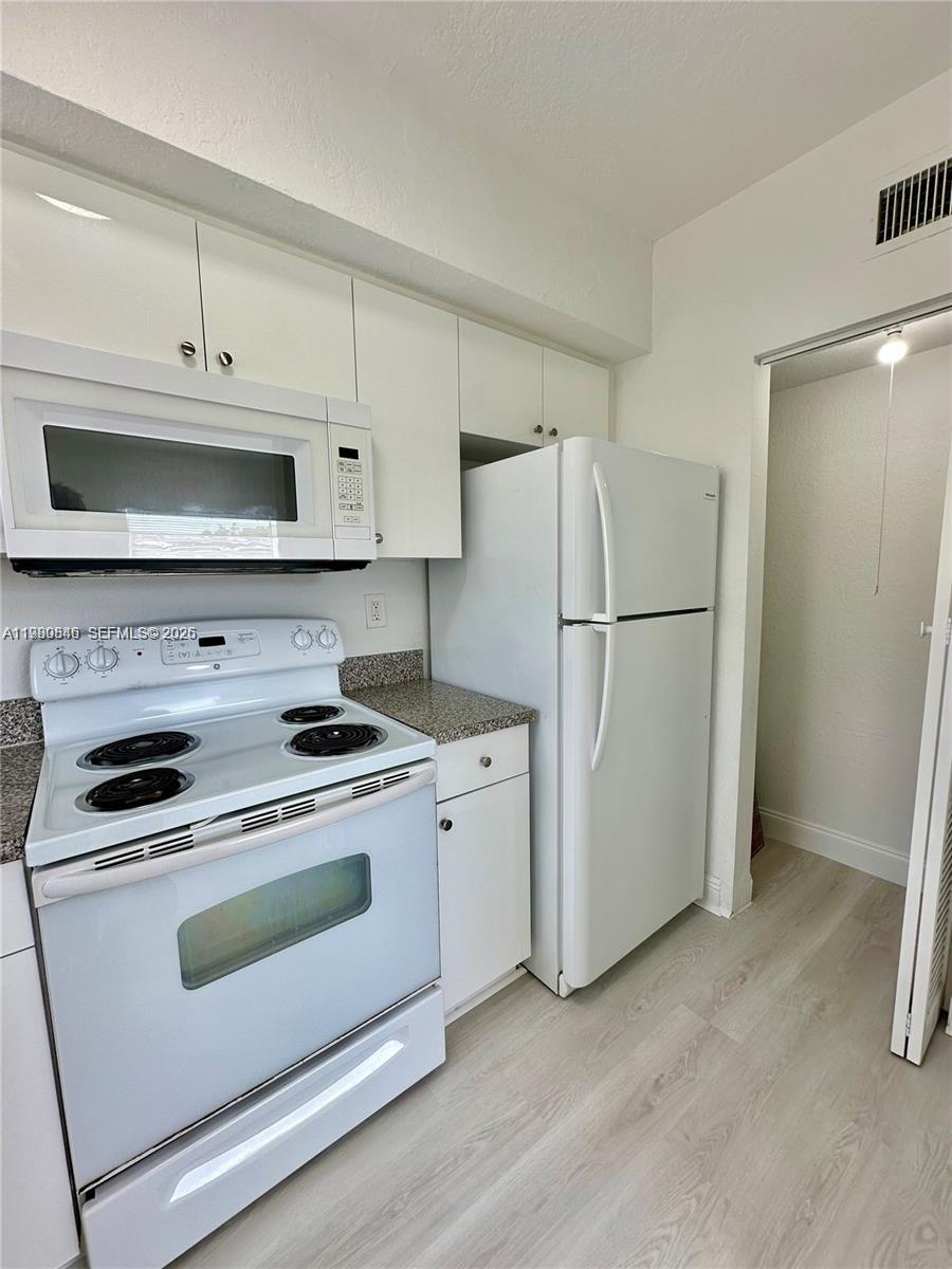 434 Northwest 85th Street Road, Unit 434 Miami, FL 33150 - Photo 7 of 31 a kitchen with white cabinets and white stainless steel appliances and a refrigerator