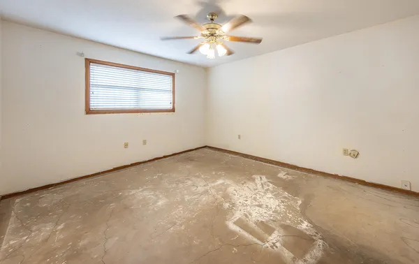 an empty room with a chandelier fan and windows