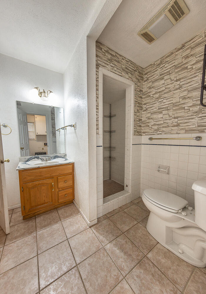 505 Owen Street Lubbock, TX 79403 - Photo 14 of 32 a bathroom with a granite countertop sink a toilet and shower