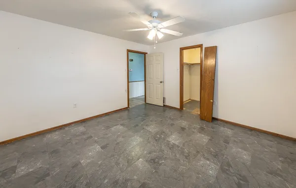 an empty room with a ceiling fan and a window