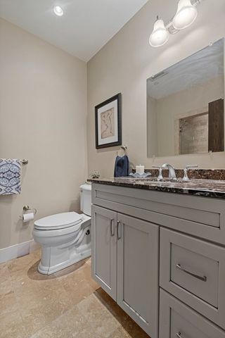 a bathroom with a granite countertop toilet sink and mirror