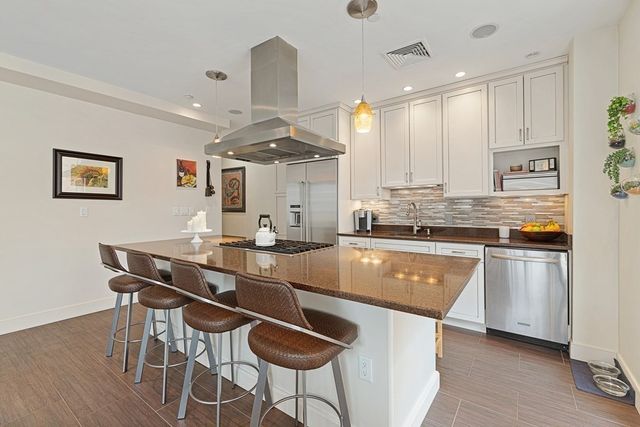 a kitchen with stainless steel appliances granite countertop a stove a sink dishwasher and a refrigerator with wooden floor