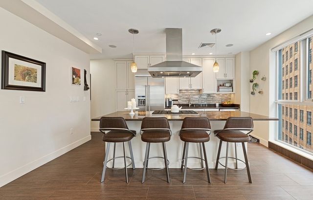 a kitchen with stainless steel appliances kitchen island granite countertop a dining table chairs and a large window
