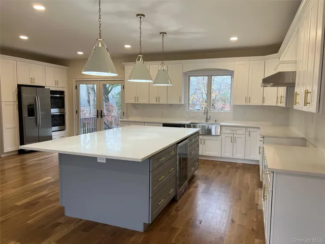 a large kitchen with stainless steel appliances granite countertop a sink a counter space and wooden floor