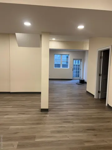 a view of an empty room with window and wooden floor