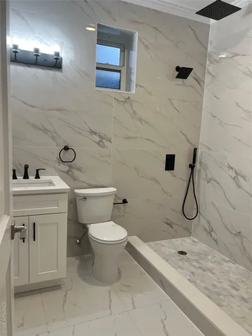 a bathroom with a granite countertop toilet sink and mirror