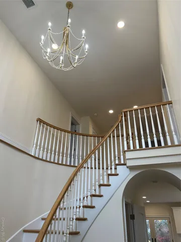 a view of staircase with railing and a chandelier