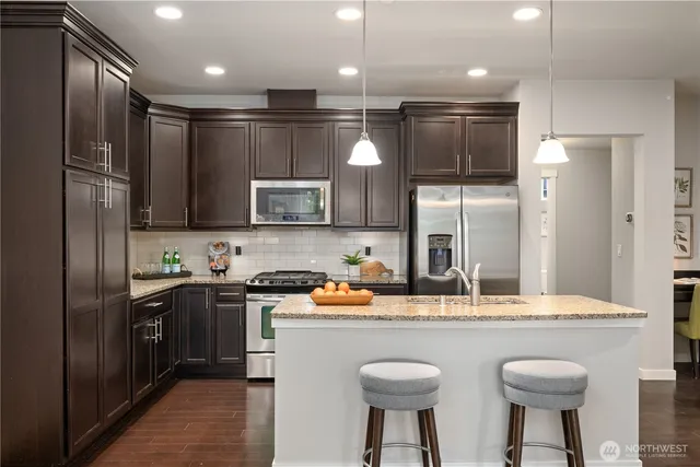 a kitchen with granite countertop a sink cabinets and stainless steel appliances
