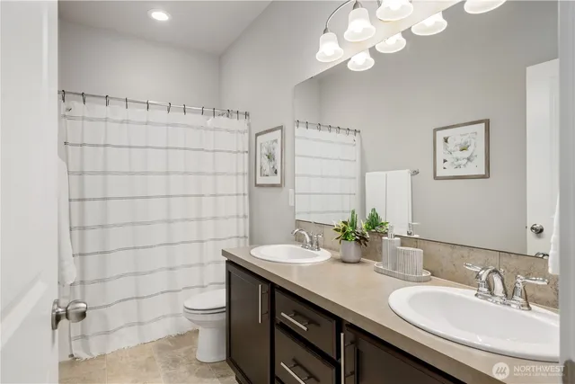 a bedroom with a bed a lamps and a large mirror on a dresser