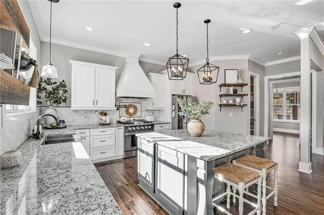 a kitchen with stainless steel appliances granite countertop a stove a sink a kitchen island with a stove and white cabinets