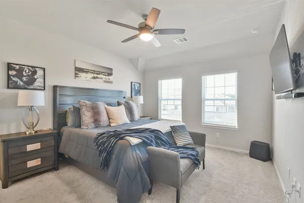 a bedroom with a bed a window and a flat screen tv