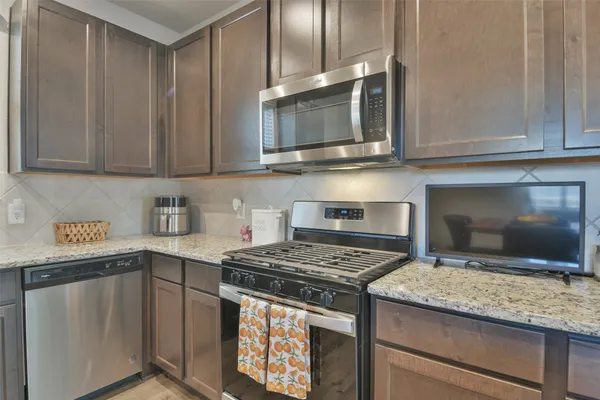 a kitchen with stainless steel appliances granite countertop a stove a sink and a microwave