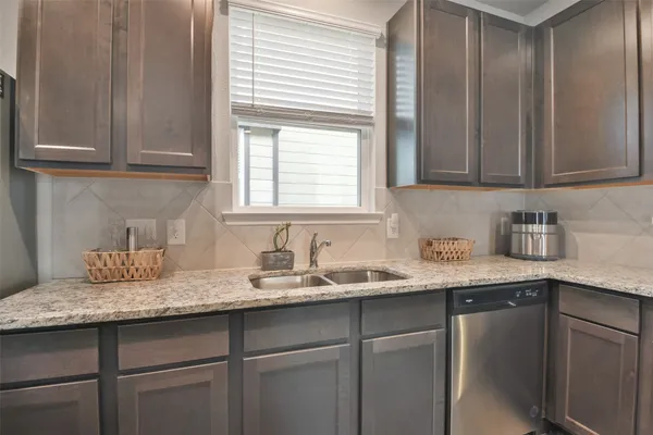 a kitchen with granite countertop stainless steel appliances white cabinets sink and window