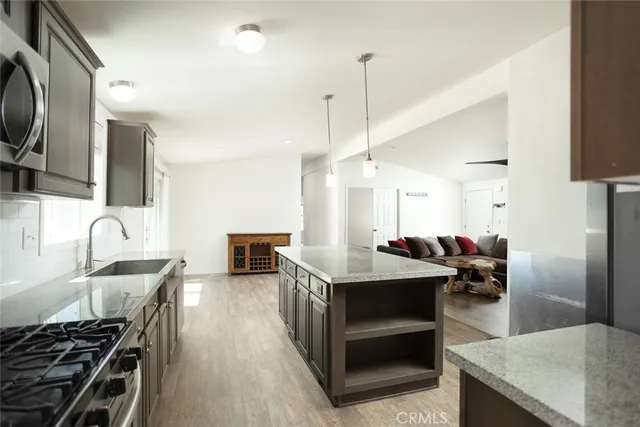 a kitchen with stainless steel appliances granite countertop a stove top oven a sink dishwasher a dining table and chairs with wooden floor