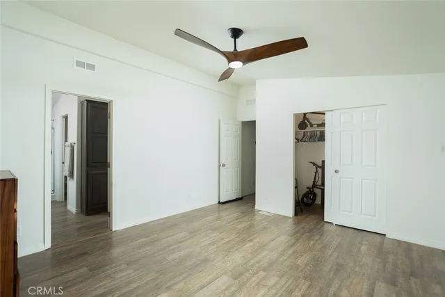 a view of a hallway with wooden floor and a ceiling fan