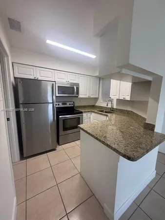 a kitchen with kitchen island a counter top space cabinets and stainless steel appliances