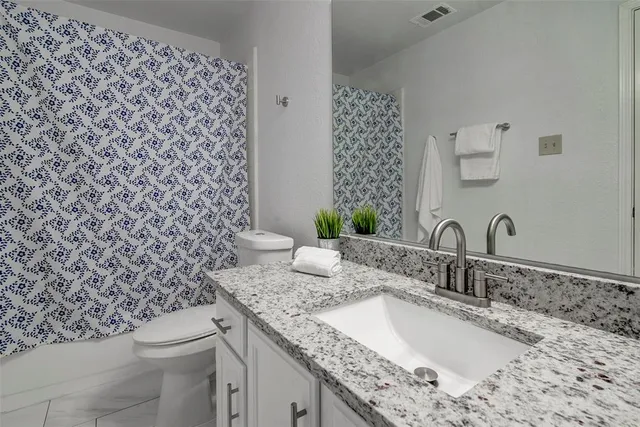 a bathroom with a granite countertop sink and a toilet