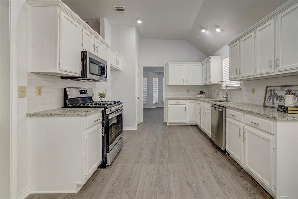 815 Fairlawn Street Allen, TX 75002 - Photo 7 of 22 a kitchen with stainless steel appliances granite countertop a stove top oven a sink a refrigerator white cabinets and wooden floor