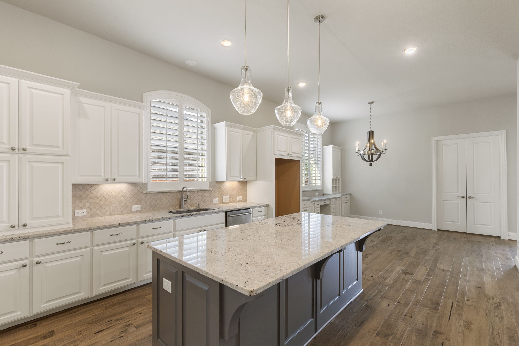 25002 Rosa Aurora Way Spring, TX 77389 - Photo 11 of 38 This spacious kitchen features elegant white cabinetry, a large central island with granite countertops, and modern pendant lighting.