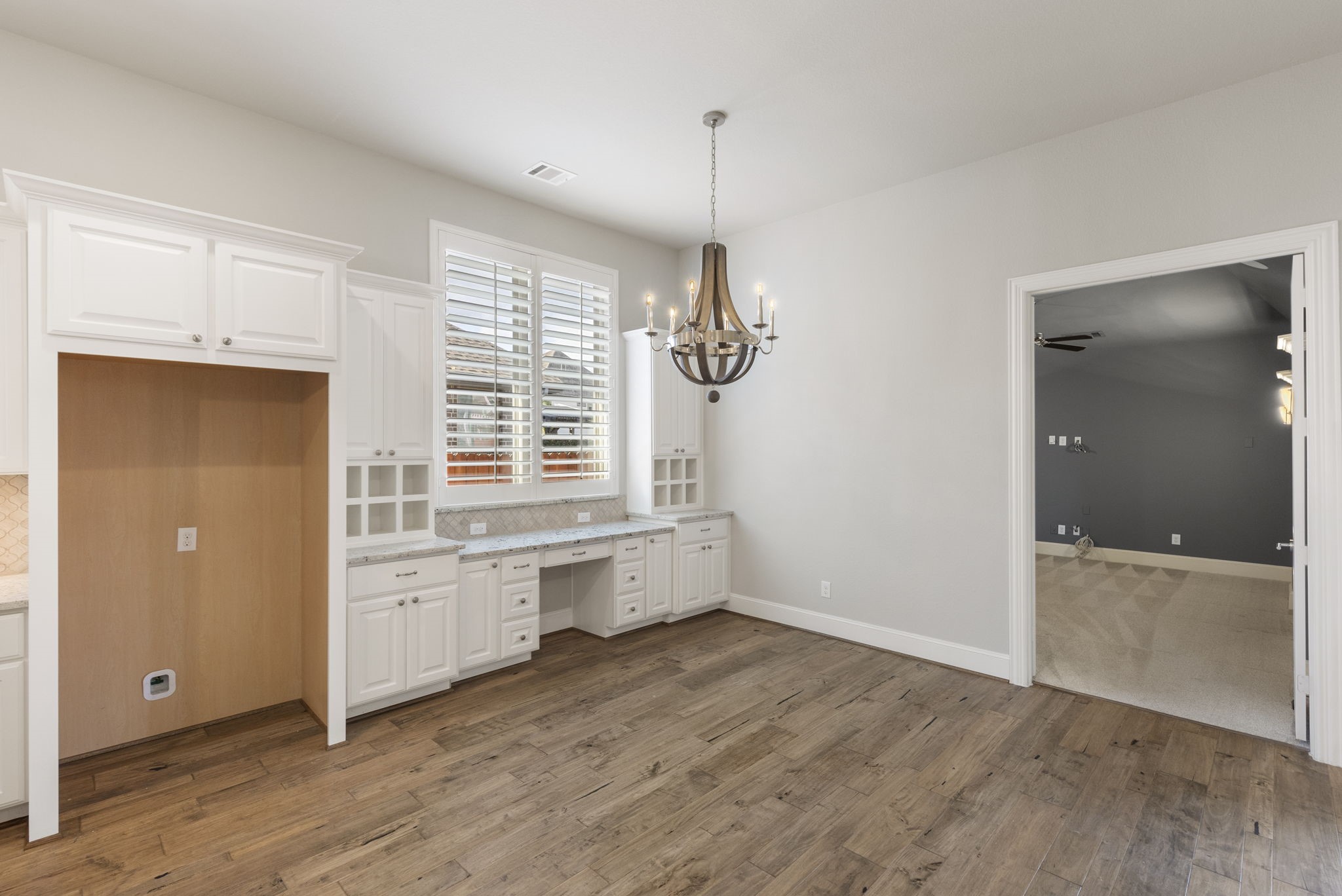 25002 Rosa Aurora Way Spring, TX 77389 - Photo 13 of 38 The breakfast area features elegant hardwood flooring, white cabinetry with ample storage, and a stylish chandelier.