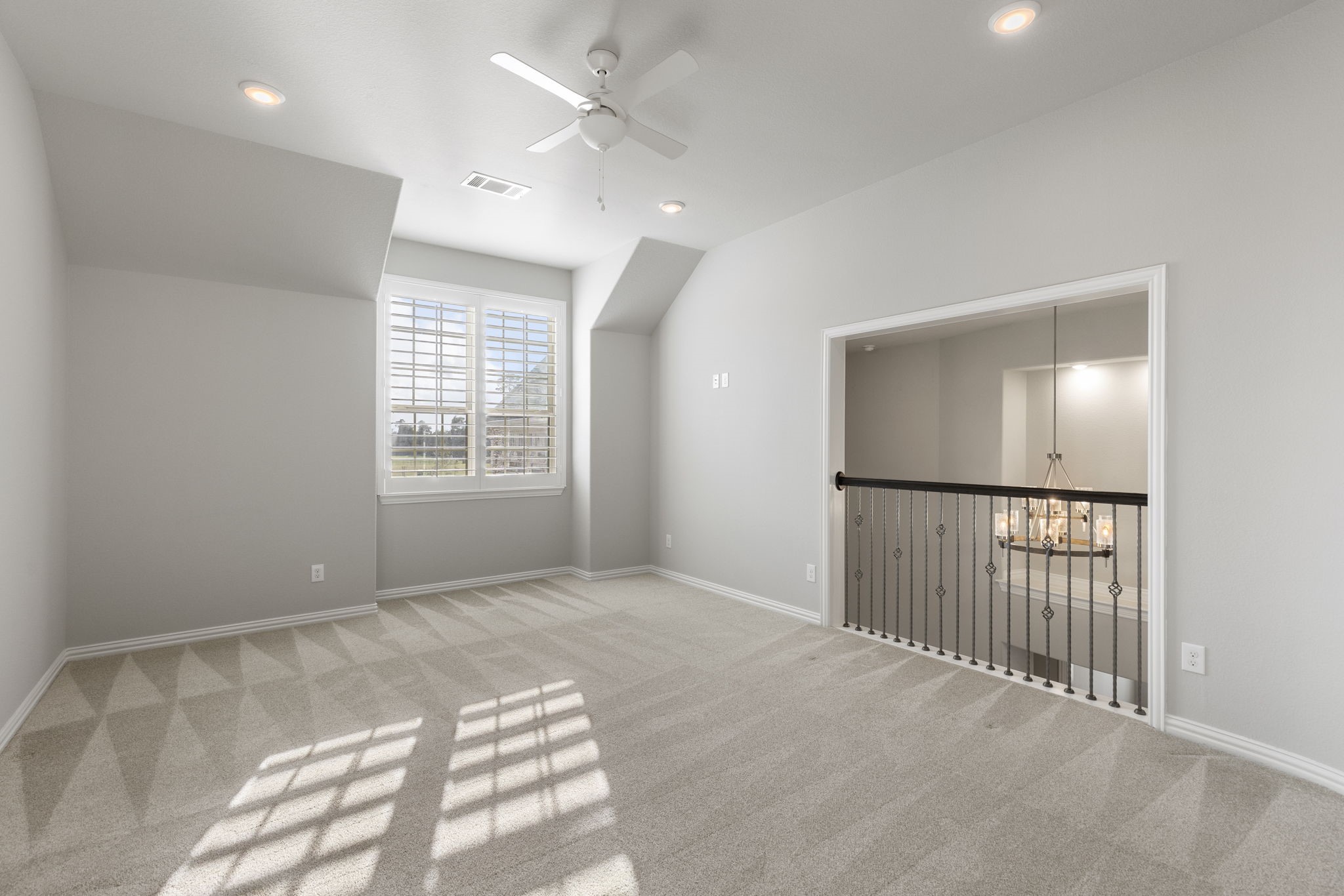 25002 Rosa Aurora Way Spring, TX 77389 - Photo 26 of 38 This spacious, game room features a large window with shutters, allowing plenty of natural light. It has a ceiling fan, recessed lighting, and a view overlooking the area below through a decorative railing, adding an open and airy feel.