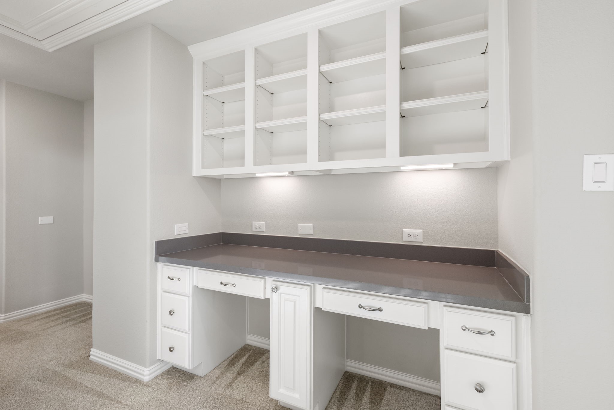25002 Rosa Aurora Way Spring, TX 77389 - Photo 28 of 38 This photo shows a built-in workspace with a sleek gray countertop, ample storage, and open shelving above.