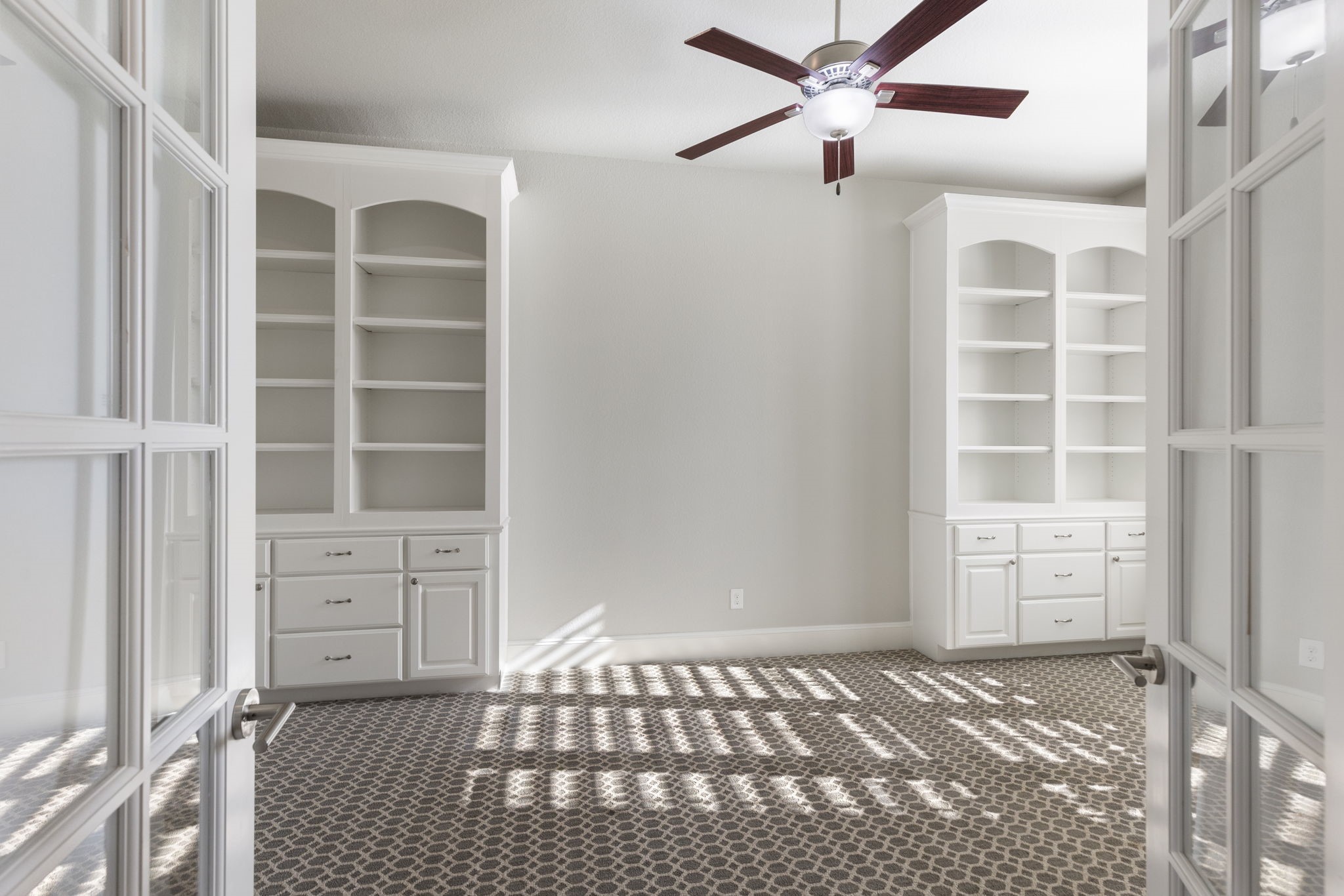 25002 Rosa Aurora Way Spring, TX 77389 - Photo 7 of 38 The office features built-in white shelving and cabinets, a patterned carpet, and a ceiling fan.