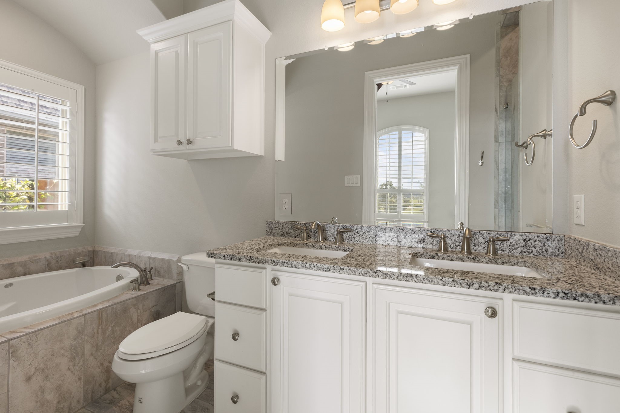 25002 Rosa Aurora Way Spring, TX 77389 - Photo 9 of 38 This en-suite features a spacious double vanity with granite countertops, a large mirror, and elegant lighting.