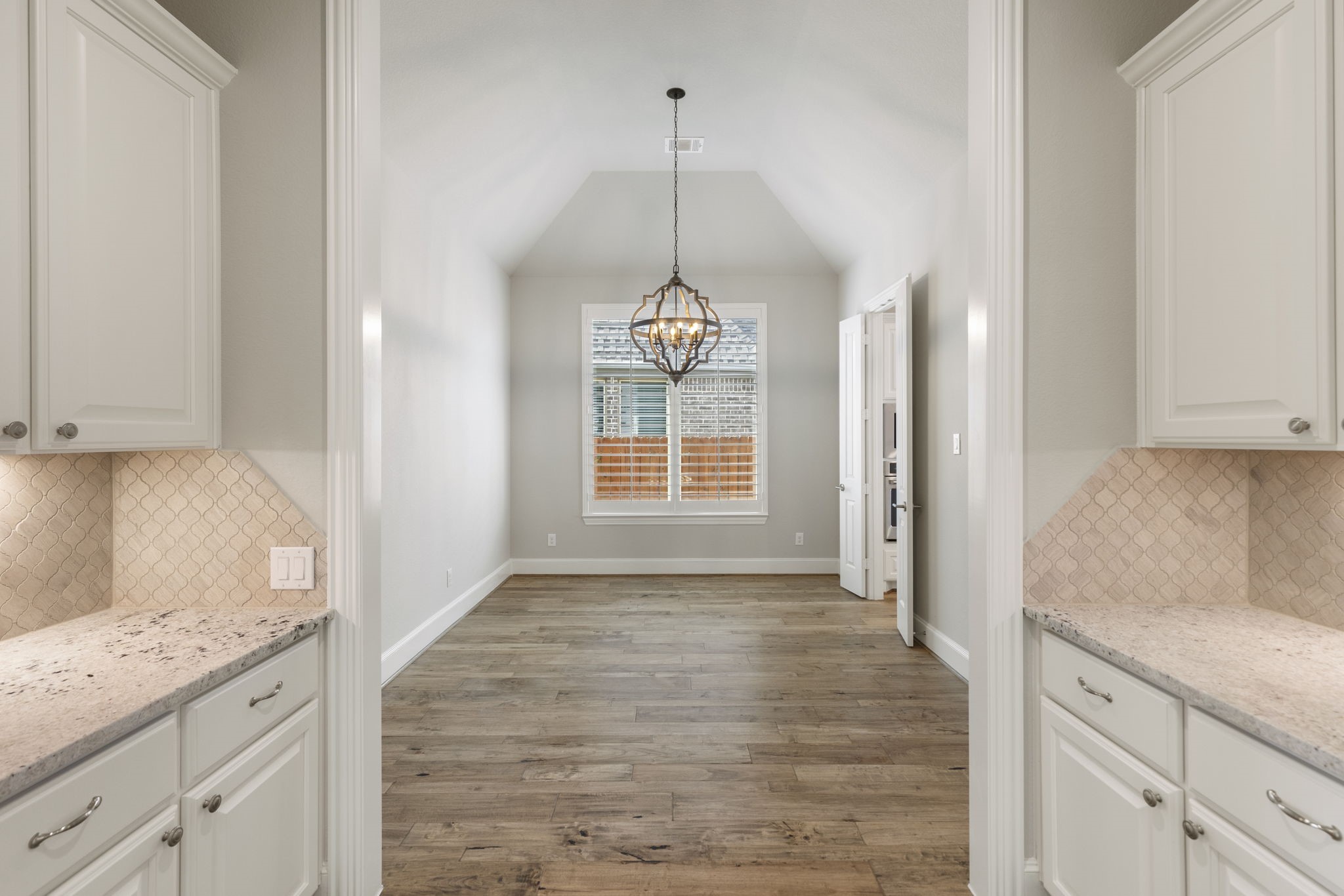 25002 Rosa Aurora Way Spring, TX 77389 - Photo 10 of 38 The space opens to a dining area featuring hardwood floors, a large window, and a stylish pendant light, creating an inviting and functional layout.