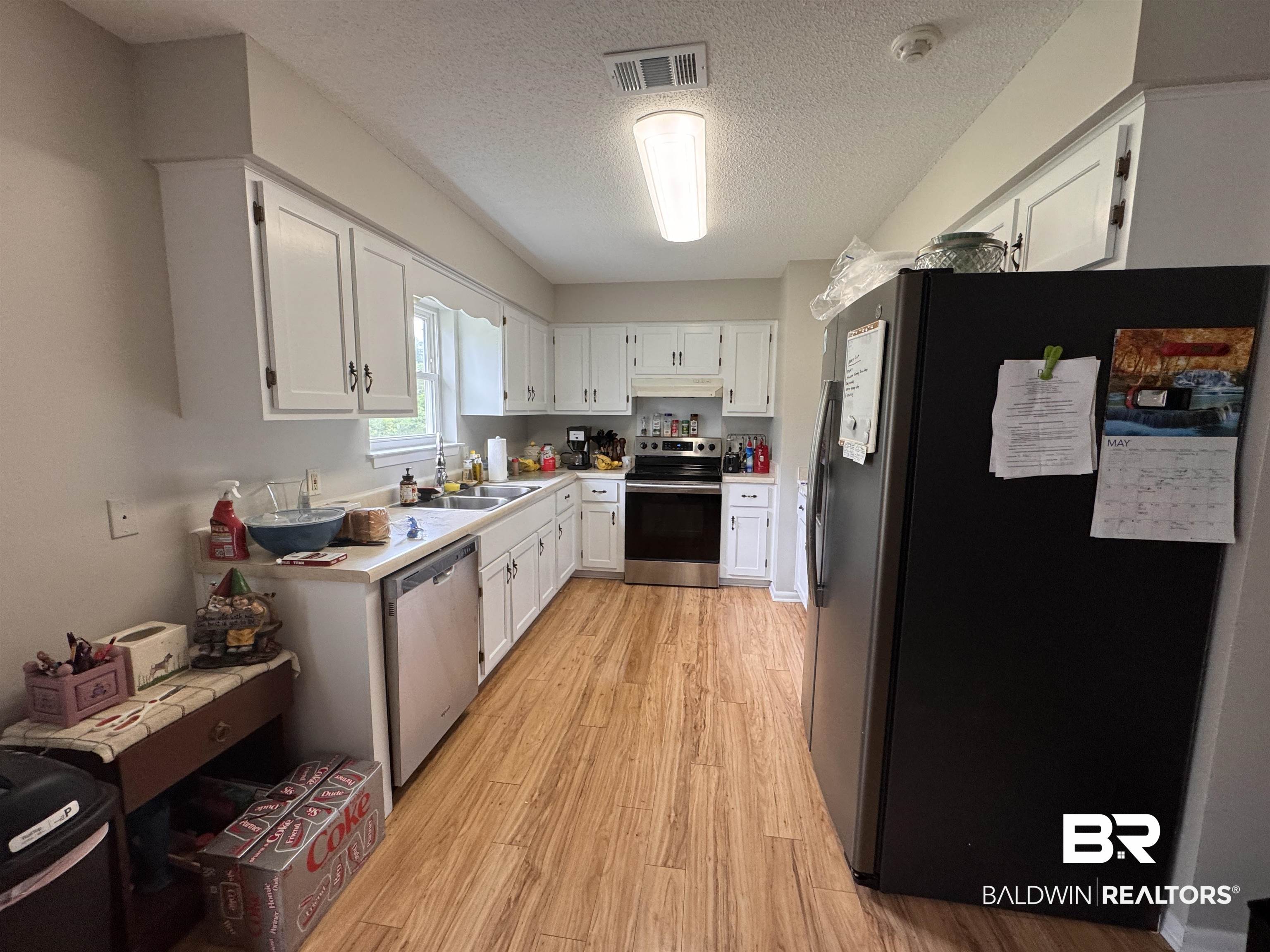 15148 Highland Circle Foley, AL 36535 - Photo 20 of 47 Kitchen with appliances with stainless steel finishes, light wood-type flooring, under cabinet range hood, white cabinets, and a textured ceiling