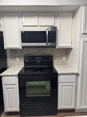 a kitchen with granite countertop white cabinets and black appliances