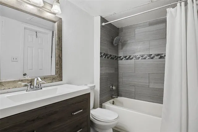 a bathroom with a bathtub shower sink vanity and toilet
