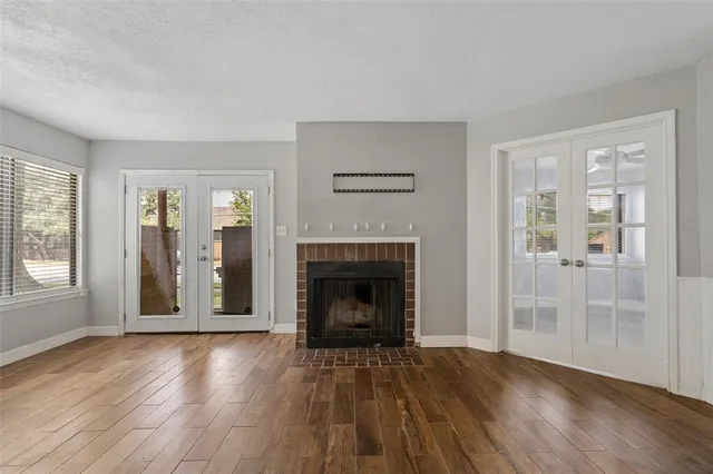 an empty room with wooden floor fireplace and windows