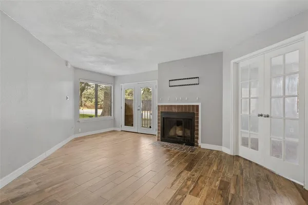 an empty room with wooden floor a fireplace and windows