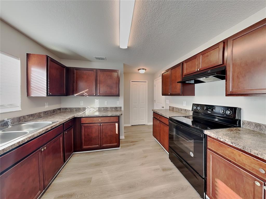 Undisclosed Address Spring Hill, FL 34609 - Photo 4 of 15 a large kitchen with stainless steel appliances granite countertop wooden cabinets a stove top oven a granite counter tops and a view of living room