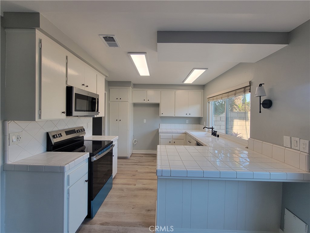 14325 Blackpool Road Westminster, CA 92683 - Photo 10 of 28 a large kitchen with kitchen island a sink stainless steel appliances and cabinets