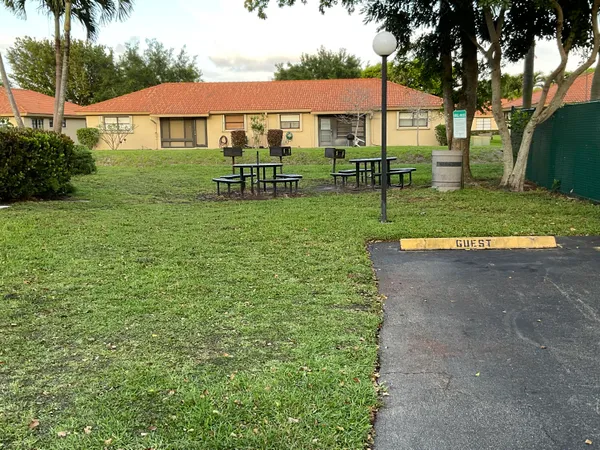 a view of a park with a table and chairs under an umbrella