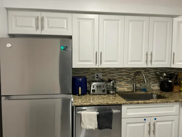 a kitchen with stainless steel appliances granite countertop white cabinets and a refrigerator