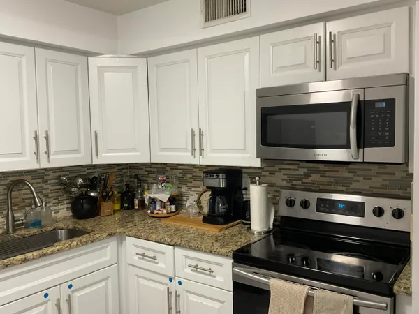 a kitchen with granite countertop white cabinets and stainless steel appliances
