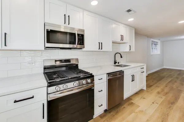 a kitchen with stainless steel appliances white cabinets and a stove top oven