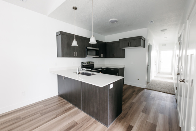 4653 South Alder Drive, Unit H303 Mapleton, UT 84664 - Photo 5 of 15 Kitchen featuring a peninsula, pendant lighting, stainless steel appliances, a textured ceiling, and modern cabinets