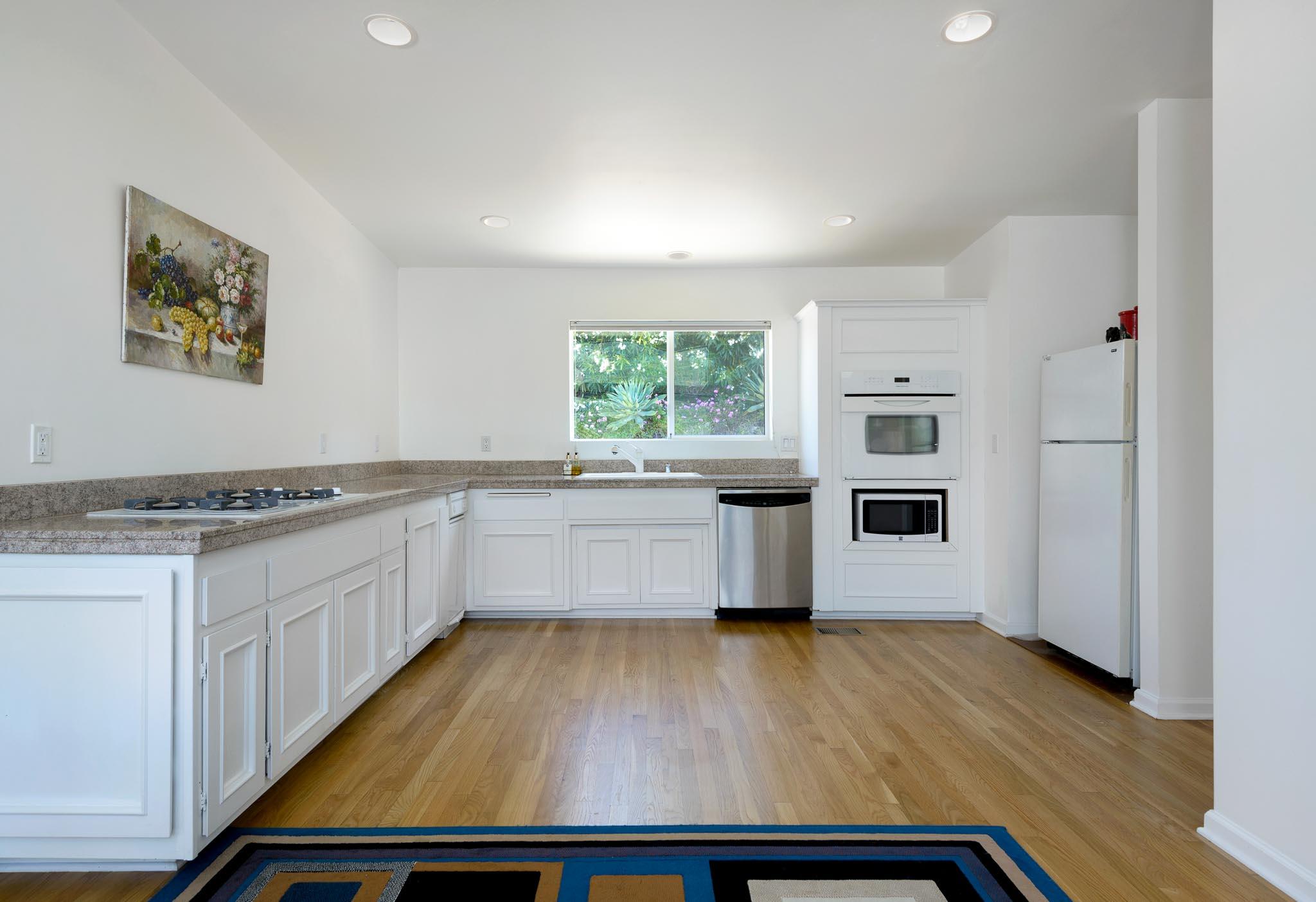 317 Conejo Road Santa Barbara, CA 93103 - Photo 4 of 15 a kitchen with wooden floors and white appliances