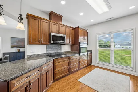 a kitchen with stainless steel appliances granite countertop sink microwave and window