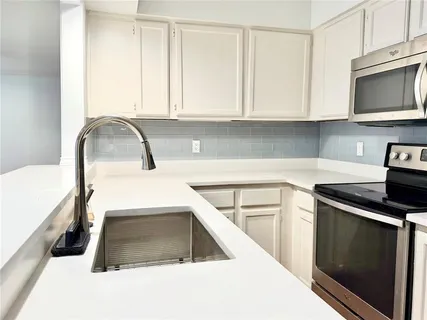 a kitchen with granite countertop white cabinets and stainless steel appliances