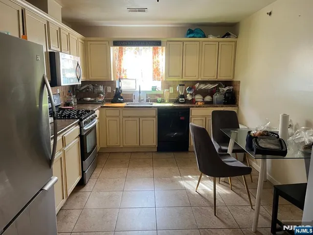 a kitchen with a stove a refrigerator and chairs